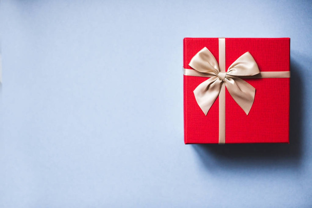 Red gift with bow on blue background top view. - 写真・画像