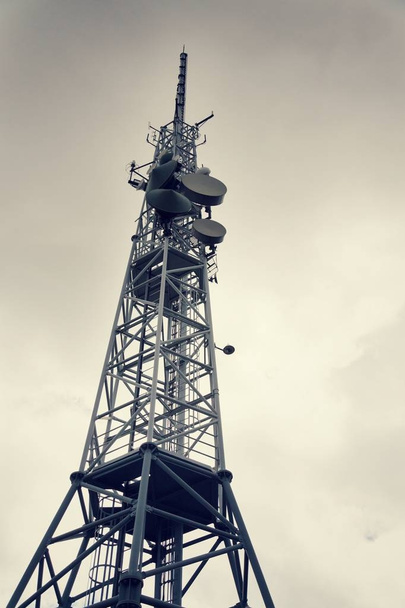 Lage-hoek vintage shot zenders en antennes op telecommunicatie toren met dramatische bewolkte hemel, digitale communicatie en codering veiligheidsconcept - Foto, afbeelding