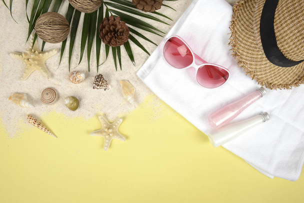 Летняя концепция и аксессуары (раковины, морская звезда, кокосовый лист) с песчаным пляжем на желтом фоне
. - Фото, изображение