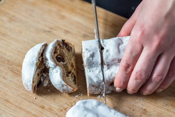 Closeup Female Hands Cutting Mini Marzipan Stollen with Knife on Wooden Board - Photo, Image