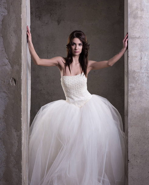 Retrato vertical de uma jovem mulher em um vestido de noiva branco com saia fofa
 - Foto, Imagem