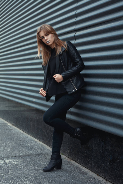 Portrait of fashionable blonde european girl wearing black leather jacket, black jeans. Posing on dark metal background. Trendy, Urban street style. Autumn Vogue Style. Toned instagram filters - Foto, Imagen