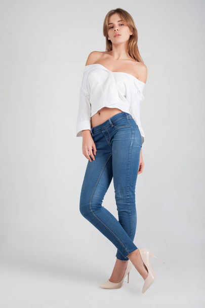 Portrait of a girl in a high fashion, beauty style with natural make up in white shirt blue jeans at silver background. Vogue style portrait. Space in background for copy, text, your words. - Fotografie, Obrázek