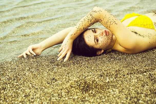 Pretty girl lies in yellow swimsuit top on sea beach - Zdjęcie, obraz