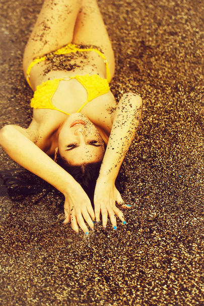 Pretty girl lies in yellow swimsuit on sea beach - Zdjęcie, obraz