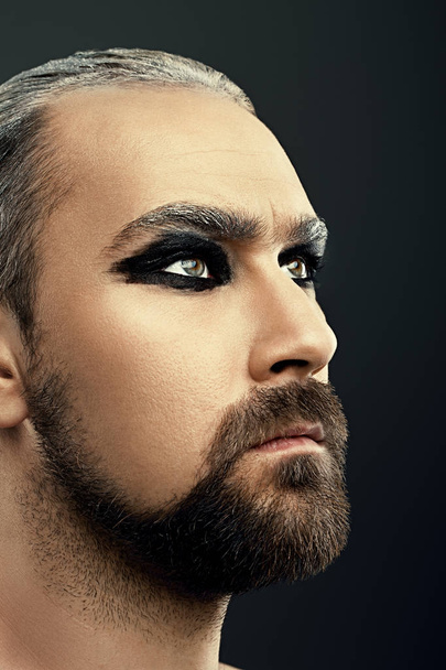 Closeup portrait of man with beard and art makeup isolated at dark background - 写真・画像