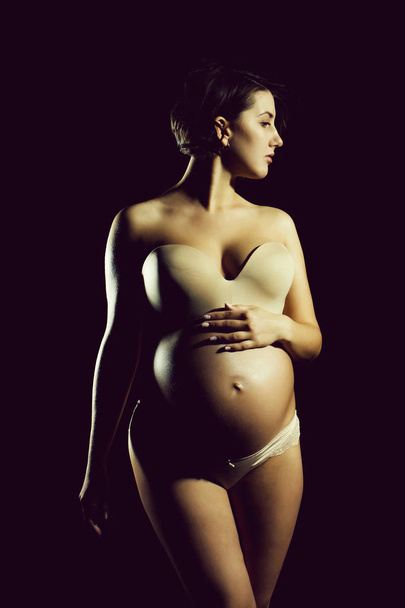 pretty pregnant woman with round belly isolated on black - Photo, image