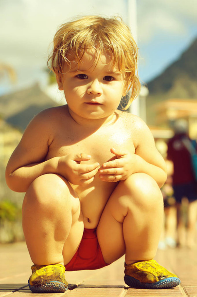 Cute baby boy sits on haunches - Φωτογραφία, εικόνα