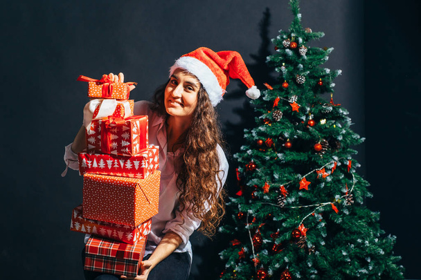 smiling woman in santa helper hat with many gift boxes - Foto, Bild
