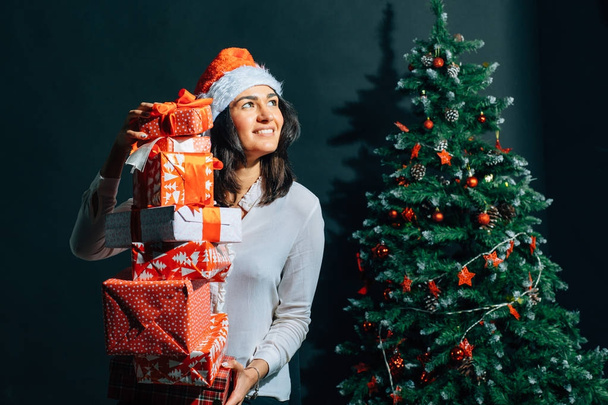 girl in santa hat near a christmas tree with gifts - Fotoğraf, Görsel