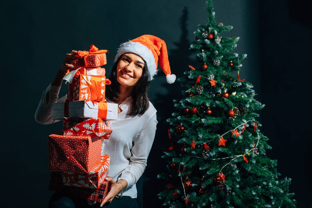 smiling woman in santa helper hat with many gift boxes - Foto, imagen