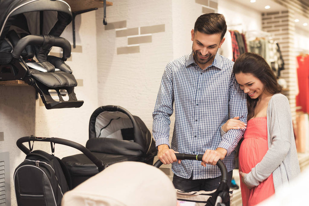 A pregnant woman together with a man choose a baby carriage. - Fotografie, Obrázek