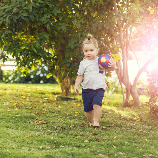 Cute baby boy playing with ball on green grass - Фото, зображення