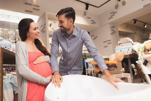 A pregnant woman with a man choose a baby bath in a store. - Zdjęcie, obraz
