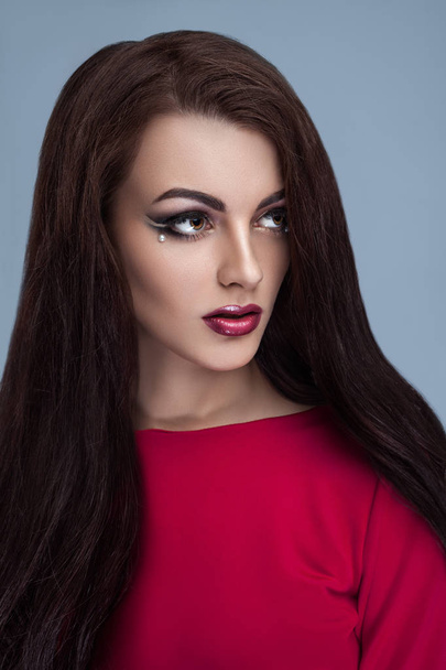 Mode brünettes Mädchen Modell posiert auf blauem Hintergrund im Studio in rotem Kleid. Make-up mit roten Lippen. Kunstdesign. getönten Stil Instagram-Filter. Mode schicke Mädchen im modischen Stil.  - Foto, Bild