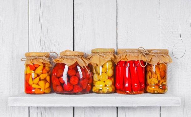 Preserved food in glass jars, on a wooden shelf - Valokuva, kuva