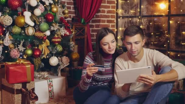Online christmas shopping. Happy young couple using credit card to shop online. Happy Young man and woman with digital tablet and credit card buying online. - Materiał filmowy, wideo