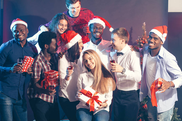 Celebrating New Year together. Group of beautiful young people in Santa hats - 写真・画像