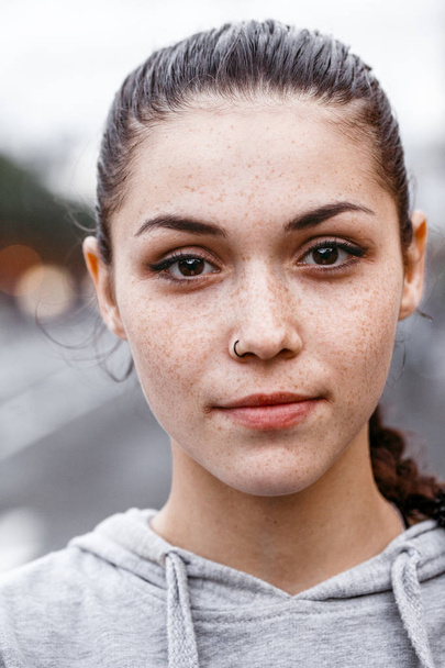 Primo piano ritratto di ragazza con un orecchino nel naso in felpa grigia per strada
 - Foto, immagini