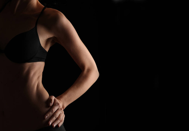 Corpo atleta feminino bonito, músculos abdominais perfeitos e oblíquos. Mulher esporte forte no fundo preto, imagem de tecla baixa
 - Foto, Imagem