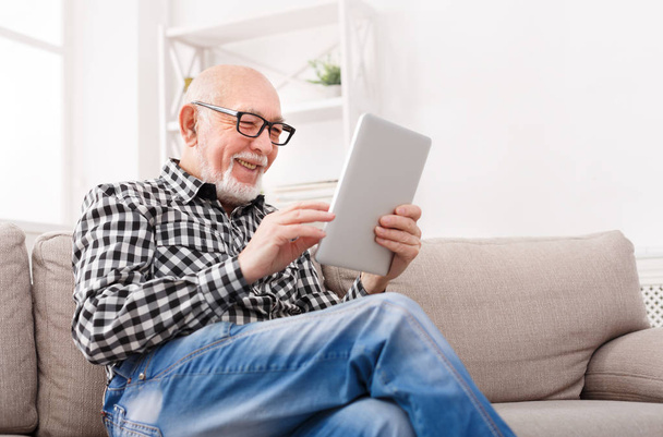 Senior man reading news on digital tablet - Foto, afbeelding