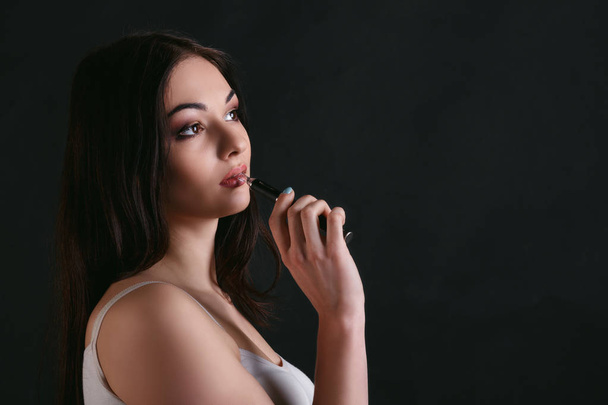Young woman vaping e-cigarette on black - Foto, afbeelding