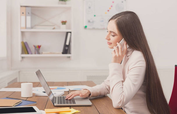 Vakava liiketoiminnan nainen töissä puhuu puhelimessa
 - Valokuva, kuva