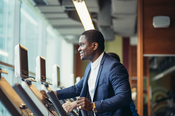 African businessman on the elliptical trainer. - Photo, image