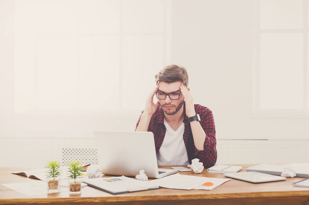 junger gestresster Geschäftsmann mit Laptop im modernen weißen Büro - Foto, Bild