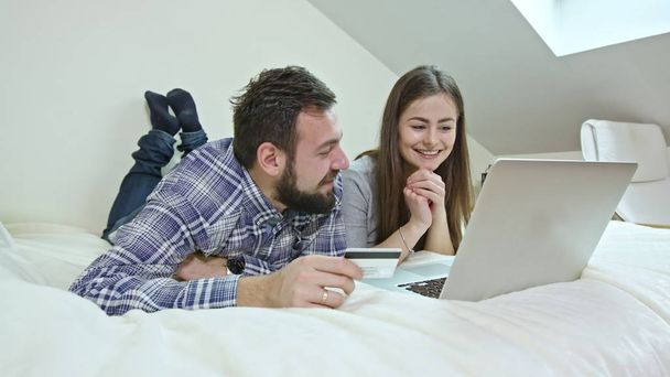 Happy Couple Using a Laptop Lying on a Bed at Home - Photo, Image
