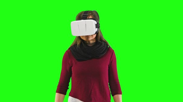 Mujer girando la cabeza con un auricular VR encendido
. - Foto, Imagen