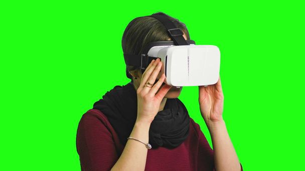 Mujer girando la cabeza con un auricular VR encendido
. - Foto, Imagen