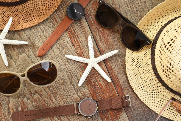 Zomer hoed en zonnebril met accessoires en sandalen op houten achtergrond - Foto, afbeelding
