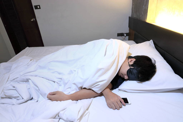 Молодий спробував азіатських людині комфортно спальний маска на ліжку в спальні вночі - Фото, зображення