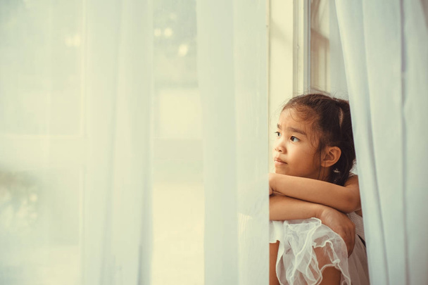 Depressed Little girl near windows at home - Foto, Imagem