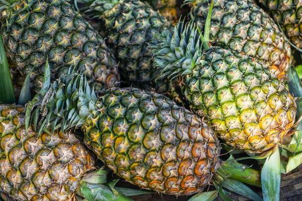 Abundance fresh juicy pineapple fruit background in yellow and green selling in local market - Zdjęcie, obraz
