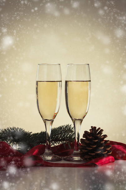 Two glasses with champagne, red ribbon, fir cone and branch. Sno - Valokuva, kuva