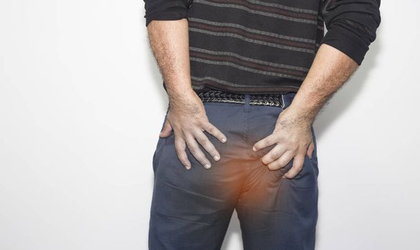 Mann mit Hämorrhoiden hält seinen Arsch vor Schmerzen - Foto, Bild