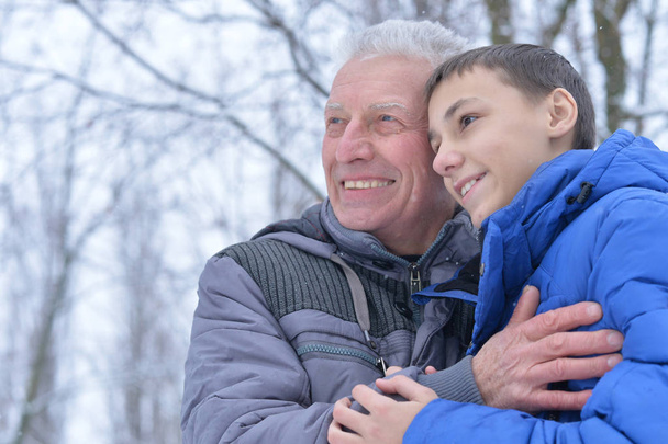 Portrait of smiling senior man and boy standing outdoors in winter - Photo, Image