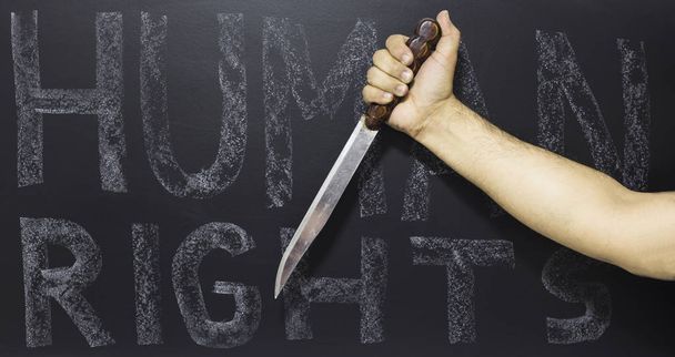 Pojęcie praw człowieka: człowiek gospodarstwa noża przeciwko tekst: dzień praw człowieka, napisany na tablicy. - Zdjęcie, obraz