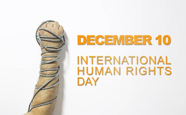 Η έννοια των ανθρωπίνων δικαιωμάτων: αλυσοδεμένος άνθρωπος κατά του κειμένου: ημέρα των ανθρωπίνων δικαιωμάτων που είναι γραμμένο στον μαυροπίνακα. - Φωτογραφία, εικόνα