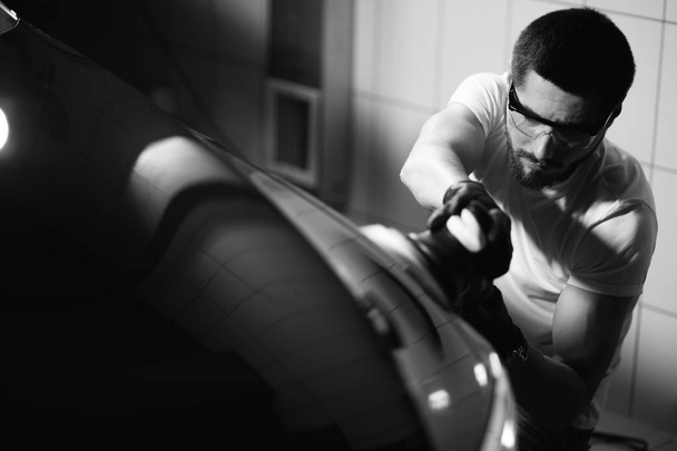 Car detailing - man with orbital polisher in auto repair shop. Selective focus. - Photo, image