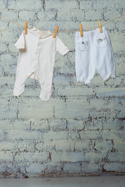 Childrens wit lichaam en panty drogen op een touw tegen een witte muur. - Foto, afbeelding