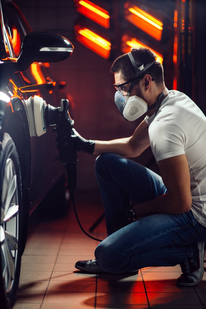 Car detailing - man with orbital polisher in auto repair shop. Selective focus. - Foto, Imagem
