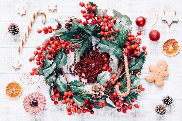 Christmas wreath and festive decorations on old white wooden table. - Фото, изображение