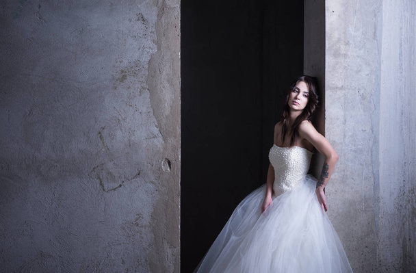 Bride in wedding dress modern, poses next to a concrete wall. Nude makeup - Fotografie, Obrázek