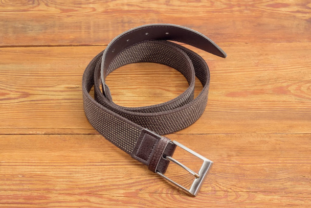 Brown stretch belt on an old wooden surface - Φωτογραφία, εικόνα