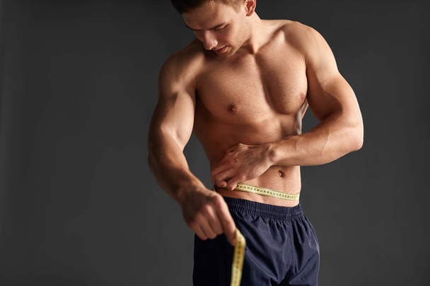 Muscular man measuring waist - Foto, Imagem