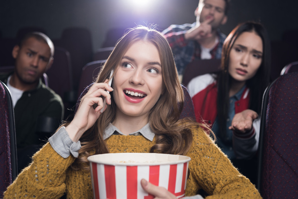 niezadowolony osoba ogląda kobieta rozmawia na smartfonie w kinie - Zdjęcie, obraz