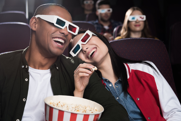 happy interracial couple in 3d glasses eaying popcorn and watching movie in cinema - Fotoğraf, Görsel